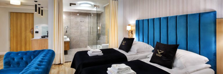 Wnętrze nowoczesnego pokoju hotelowego z dwiema łóżkami i łazienką.