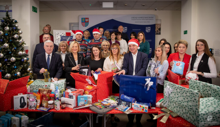 Grupa osób przy stołach z prezentami podczas akcji Szlachetna Paczka w Urzędzie Marszałkowskim Województwa Świętokrzyskiego