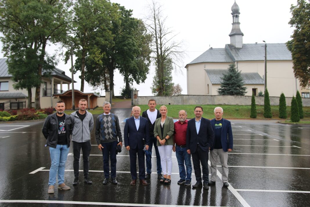 Grupa osób na tle zabytkowego kościoła w Brzezinach po zakończeniu przebudowy dojazdu
