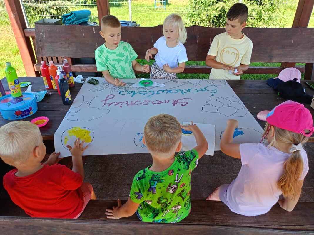 Grupa dzieci biorących udział w projekcie plastycznym na świeżym powietrzu.