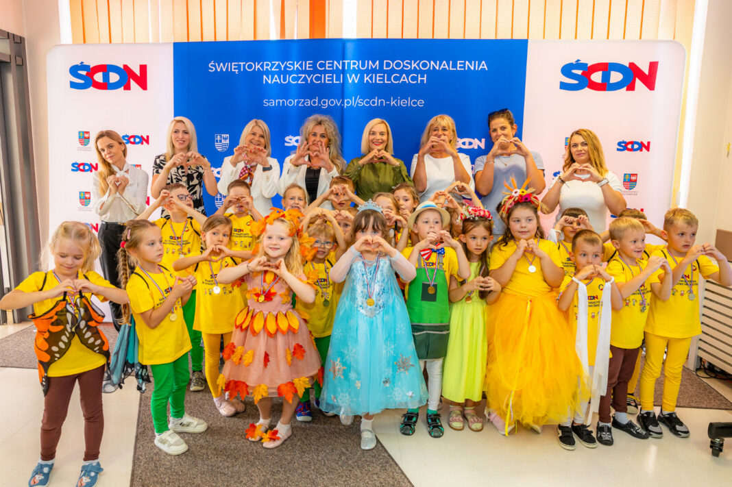 Grupa dzieci i nauczycieli przed banerem Świętokrzyskiego Centrum Doskonalenia Nauczycieli w Kielcach