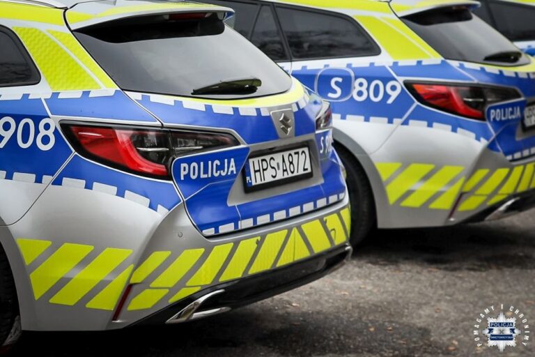 Dwa oznakowane radiowozy policyjne zaparkowane na ulicy.