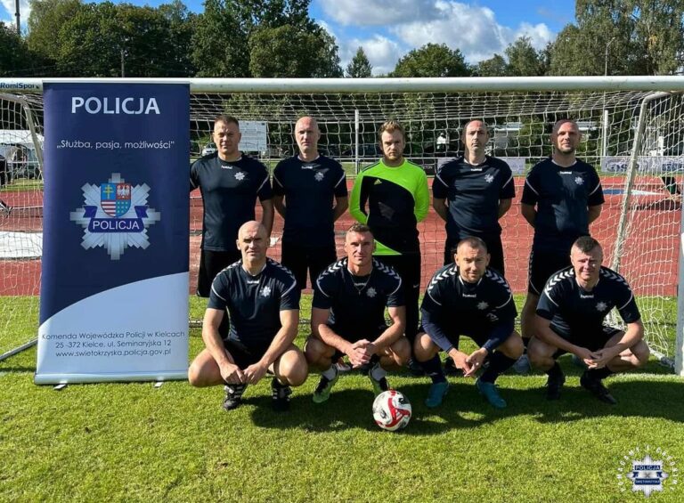 Świętokrzyscy policjanci na podium ogólnopolskiego turnieju piłkarskiego, grupa mężczyzn w strojach sportowych przed bramką.