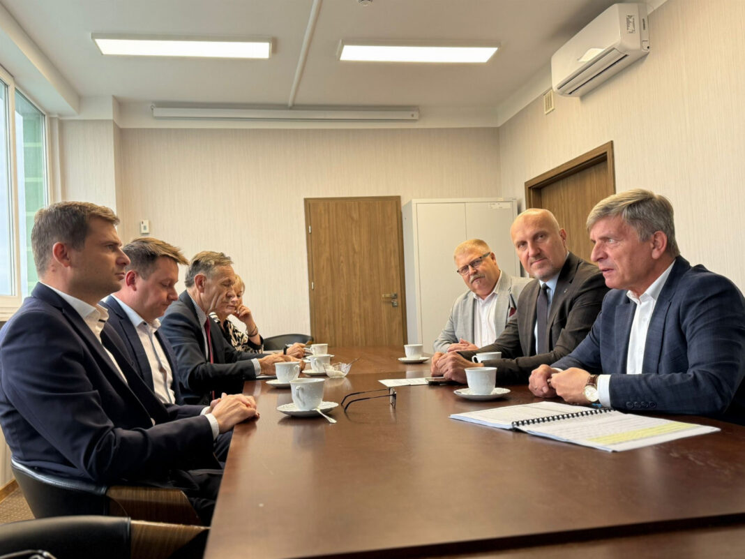 Grupa osób w formalnej odzieży siedząca przy stole w powiecie opatowskim