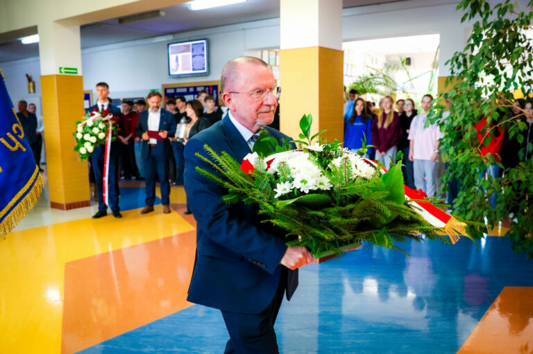 Mężczyzna z wiązanką kwiatów podczas uroczystości w szkole w Jędrzejowie
