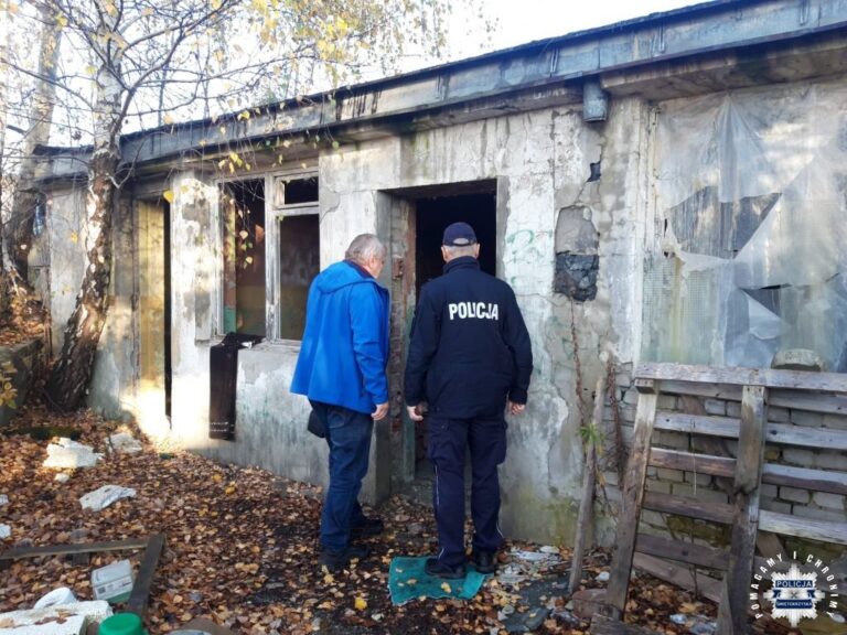 Policjant i mężczyzna w niebieskiej kurtce przed opuszczonym budynkiem.