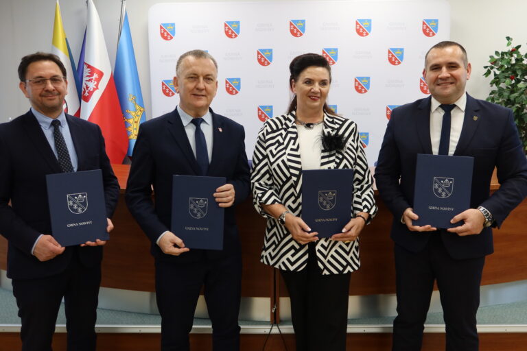 Cztery osoby trzymające dokumenty podczas podpisania partnerstwa gmin na rzecz Geoparku Świętokrzyskiego UNESCO.