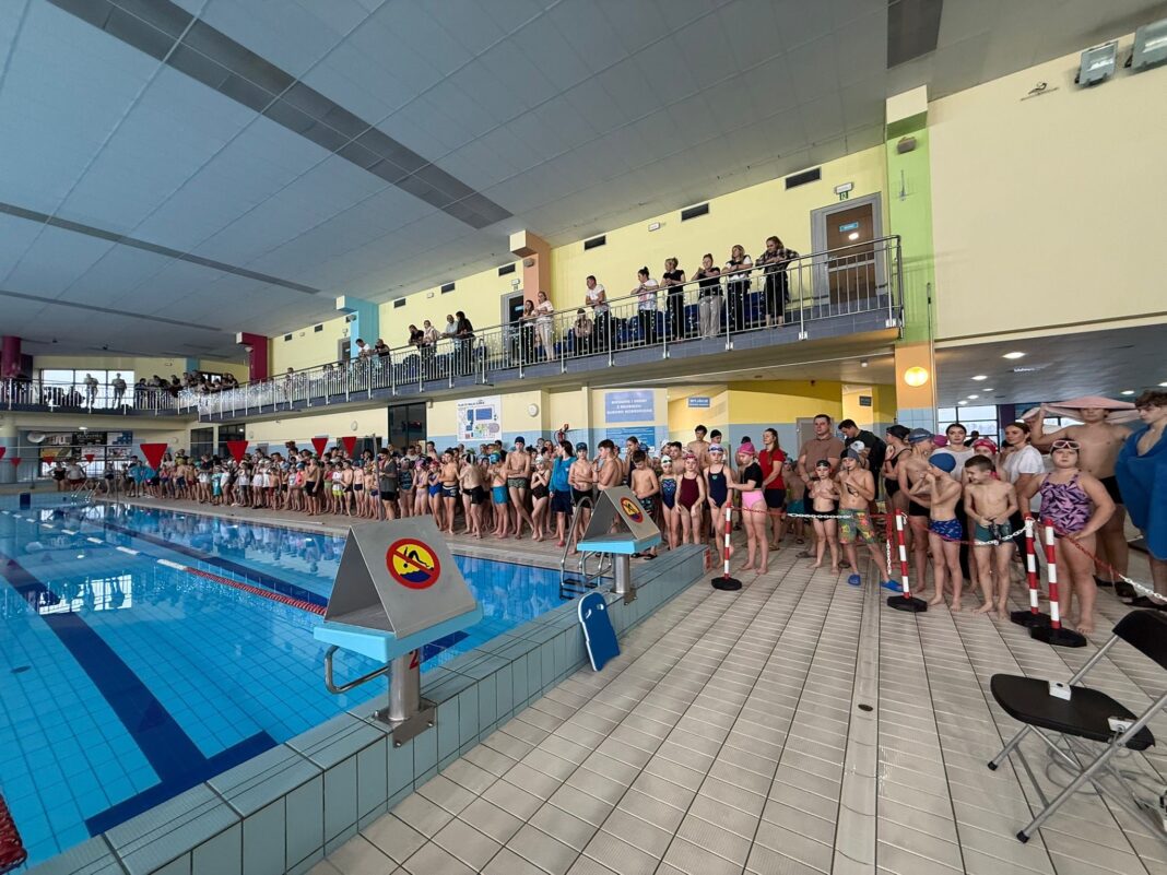 Młodzi pływacy na starcie przy basenie podczas Mikołajkowych Zawodów Pływackich w Strawczynie.