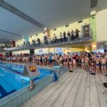 Młodzi pływacy na starcie przy basenie podczas Mikołajkowych Zawodów Pływackich w Strawczynie.