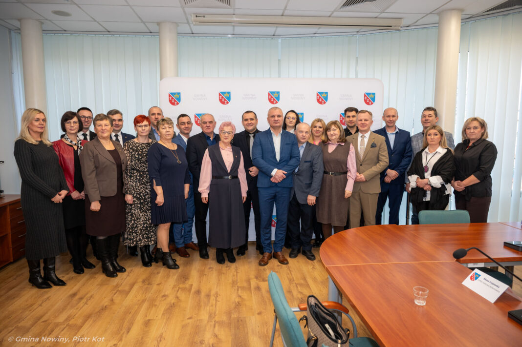 Grupa osób na tle logo Gminy Nowiny, uchwalających budżet na 2026 rok.