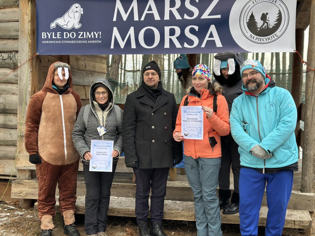 Uczestnicy Czwartym Marszu Morsa pozują na tle baneru z napisem 'Marsz Morsa'
