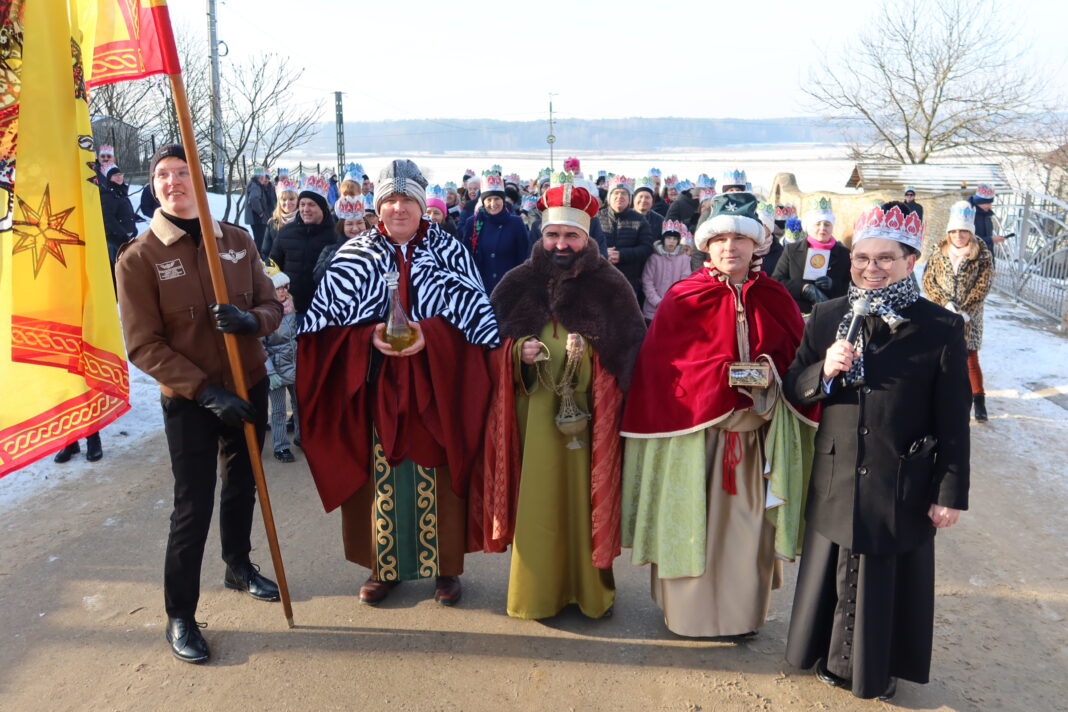Orszak Trzech Króli w Chełmcach z uczestnikami przebranymi za Trzech Króli, otoczony wiernymi.
