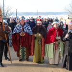 Orszak Trzech Króli w Chełmcach z uczestnikami przebranymi za Trzech Króli, otoczony wiernymi.