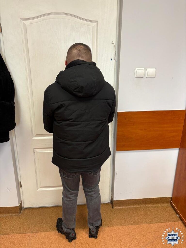 Mężczyzna w czarnej kurtce stojący tyłem w pomieszczeniu