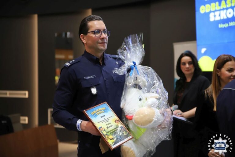 Policjant nagradzający uczestnika podczas gali Odblaskowa Szkoła