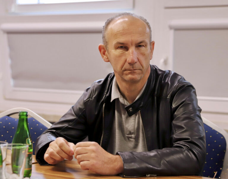 Człowiek w skórzanej kurtce siedzący przy stole podczas spotkania Komisji Skarg, Wniosków i Petycji Sejmiku Województwa