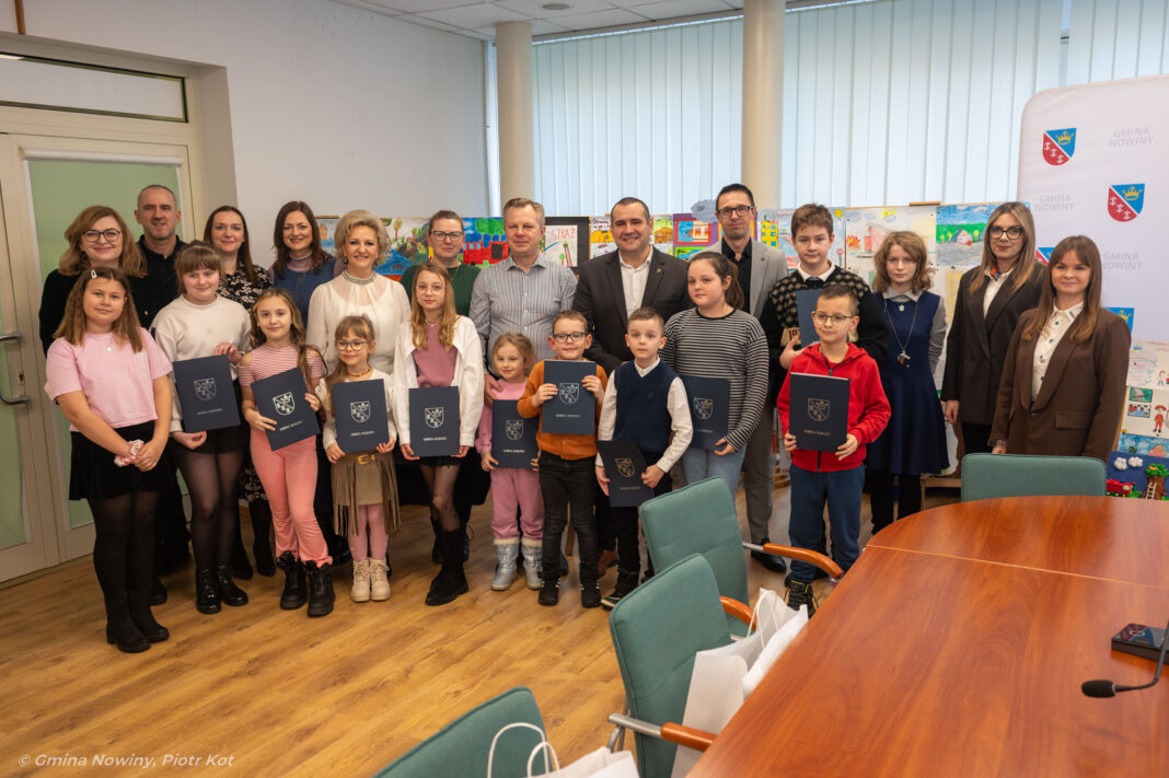 Grupa młodych artystów z Nowin wraz z opiekunami, trzymających nagrody za udział w konkursie plastycznym.