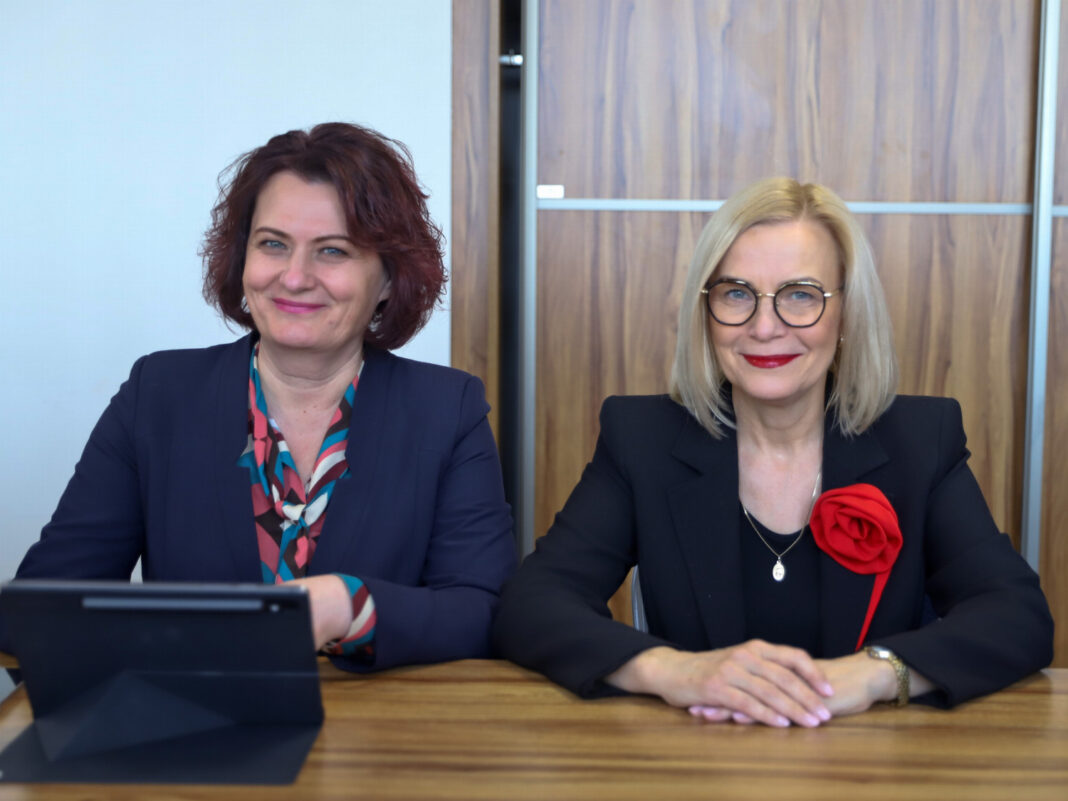 Dwie kobiety w formalnych strojach siedzące przy biurku podczas obrad Komisji Budżetu i Finansów.