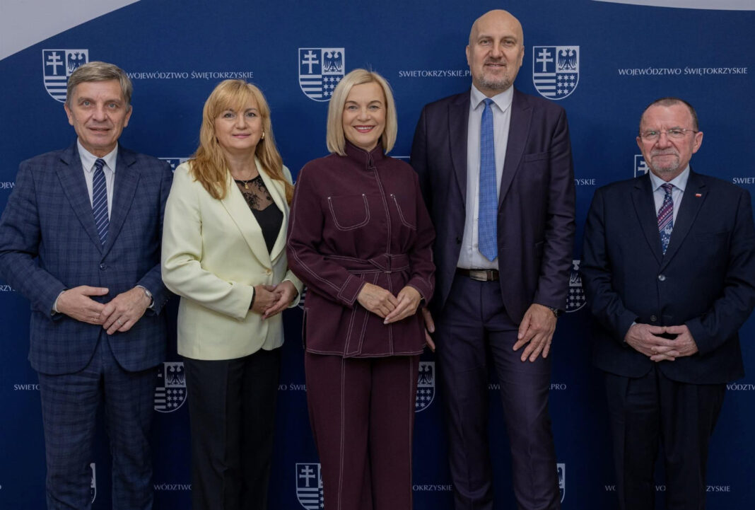 Grupa osób na oficjalnym tle z logiem Województwa Świętokrzyskiego