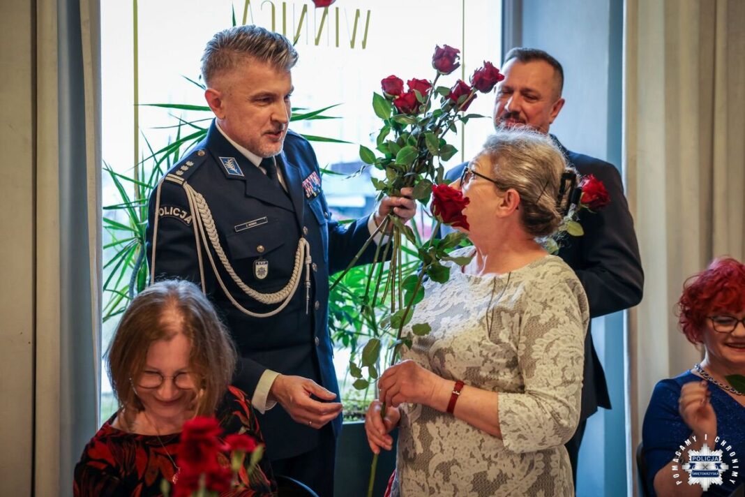Policjant wręcza różę emerytce podczas Dnia Kobiet