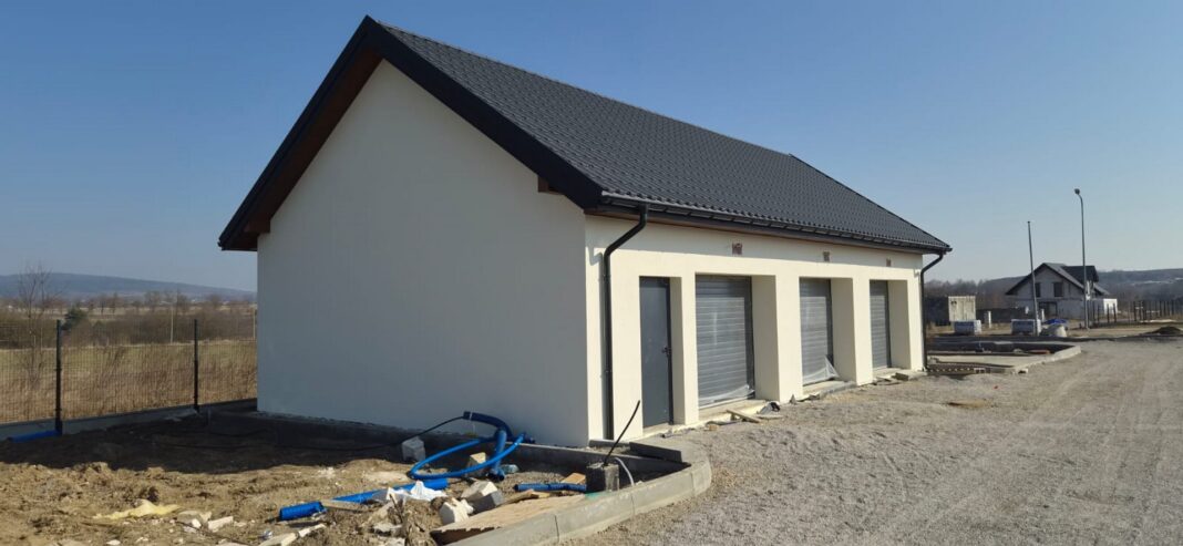 Zdjęcie przedstawia budynek w Łagowie prawie ukończony, z dachem dwuspadowym, w trakcie końcowych prac budowlanych.