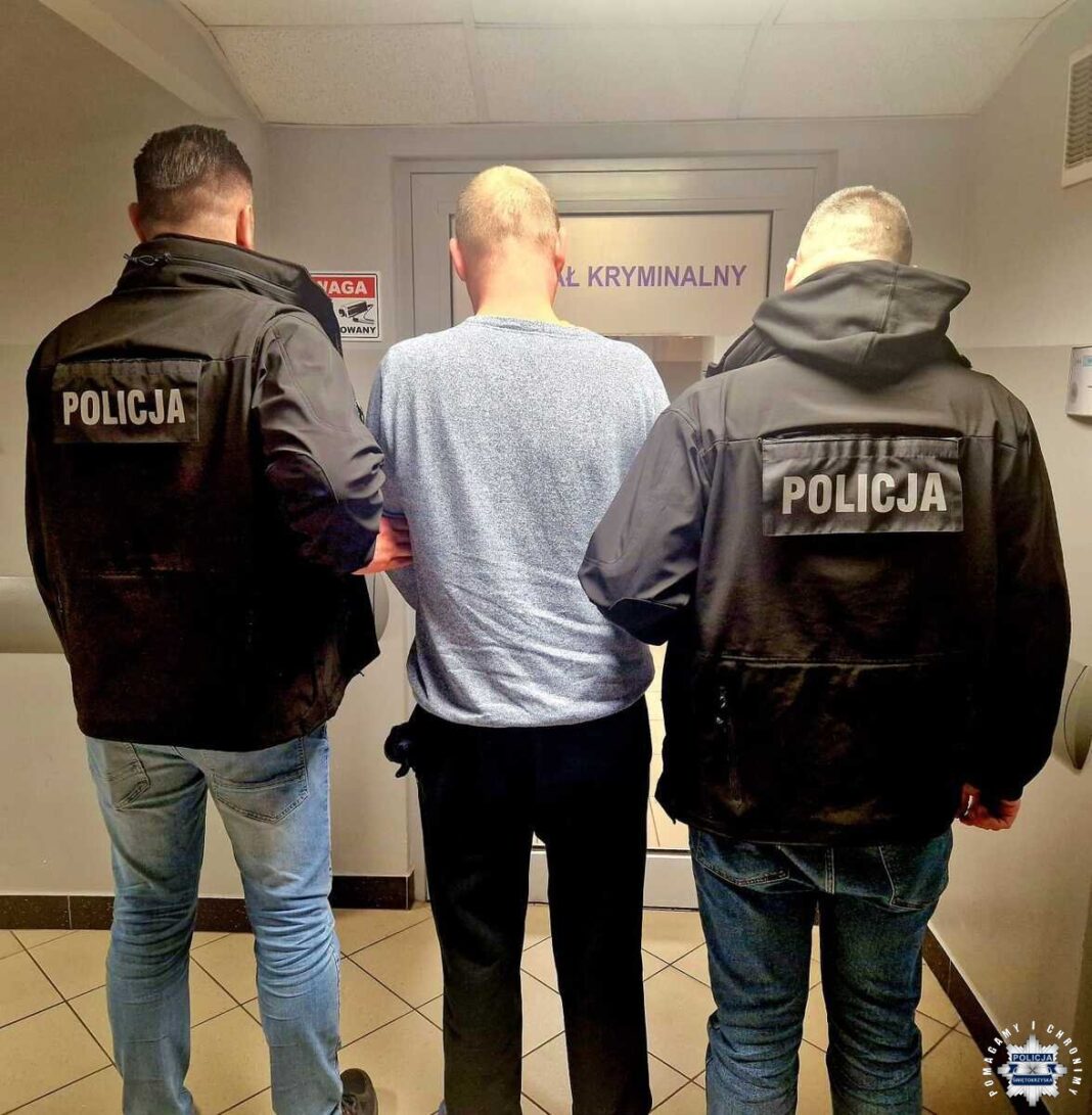 Dwóch policjantów prowadzi zatrzymanego mężczyznę korytarzem